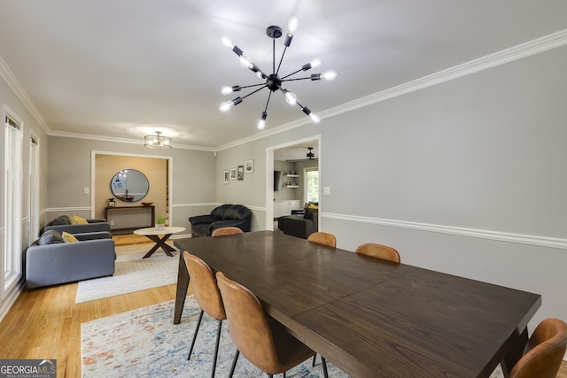 dining space featuring an inviting chandelier, ornamental molding, and light wood-type flooring