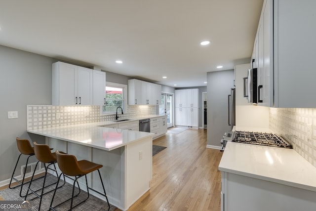 kitchen with a kitchen breakfast bar, sink, kitchen peninsula, white cabinetry, and stainless steel appliances