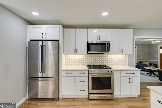 kitchen featuring appliances with stainless steel finishes, light hardwood / wood-style flooring, and white cabinetry