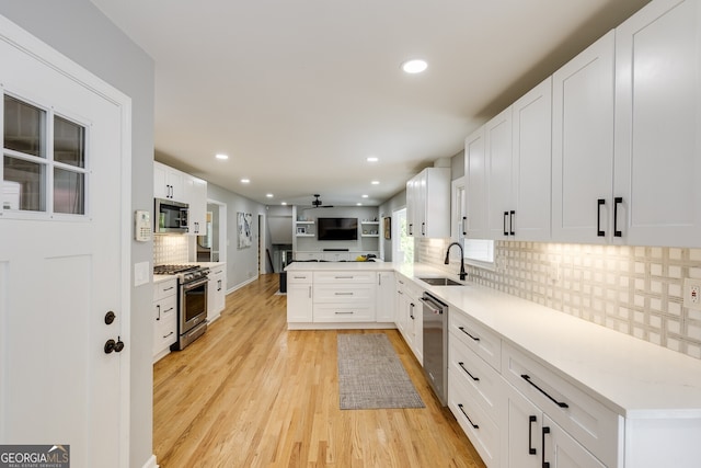 kitchen featuring white cabinets, sink, light wood-type flooring, appliances with stainless steel finishes, and kitchen peninsula