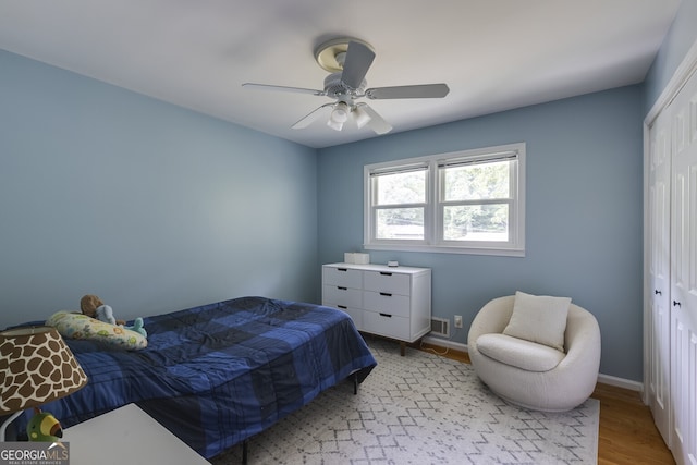 bedroom with ceiling fan, light hardwood / wood-style floors, and a closet