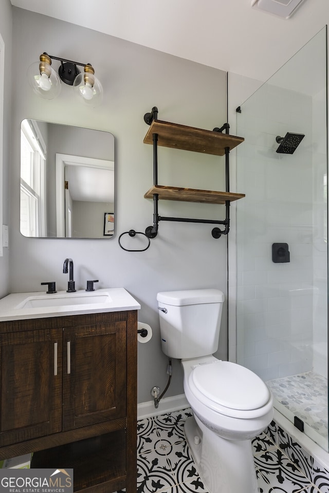 bathroom featuring tile patterned floors, toilet, a tile shower, and vanity