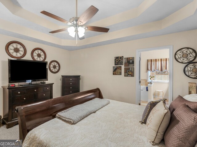 carpeted bedroom with a closet, a tray ceiling, a spacious closet, and ceiling fan