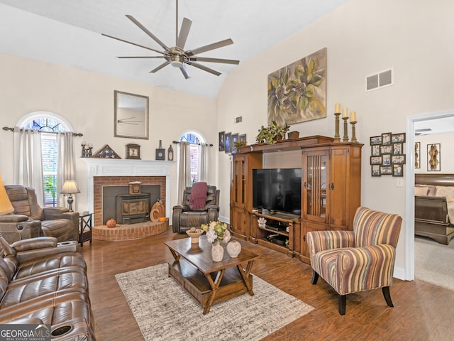 living room with ceiling fan, dark hardwood / wood-style flooring, a wood stove, and high vaulted ceiling