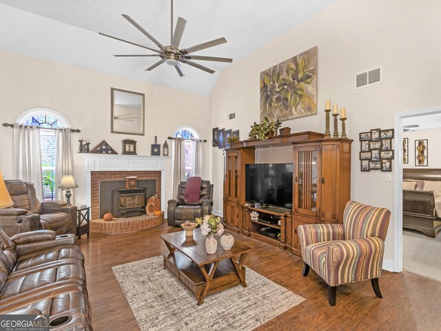 living room with ceiling fan, a healthy amount of sunlight, a wood stove, and dark wood-type flooring