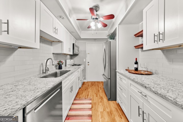 kitchen featuring decorative backsplash, light wood-type flooring, stainless steel appliances, sink, and white cabinetry