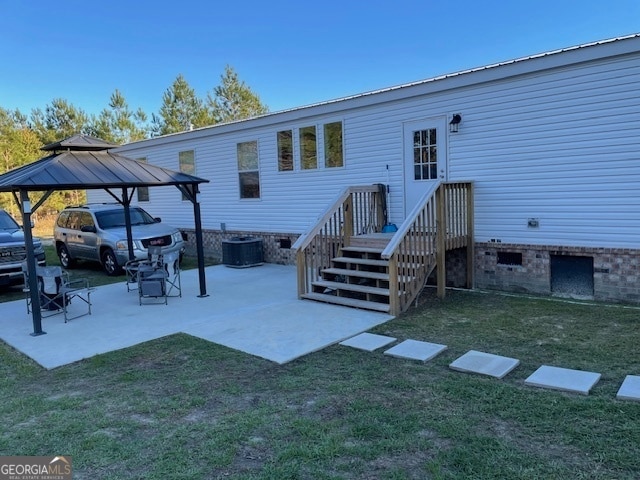 rear view of property featuring a gazebo, central AC unit, and a lawn