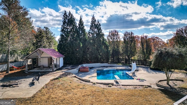 view of swimming pool with an outbuilding, a patio, and a water slide