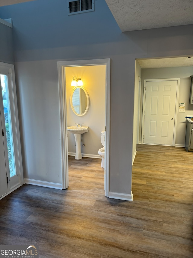 hallway featuring a textured ceiling, light hardwood / wood-style floors, and sink