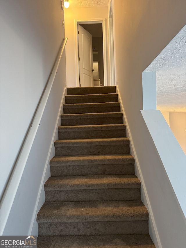 stairs with a textured ceiling