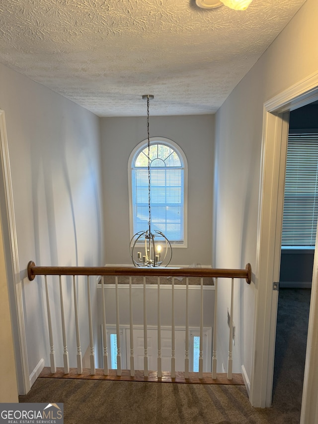 interior details featuring carpet, a chandelier, and a textured ceiling