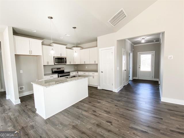 kitchen featuring white cabinetry, stainless steel appliances, dark hardwood / wood-style floors, pendant lighting, and a kitchen island with sink