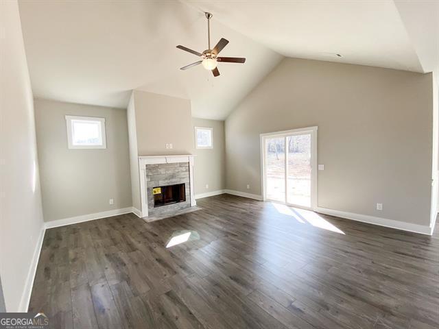 unfurnished living room with dark hardwood / wood-style flooring, high vaulted ceiling, ceiling fan, and a healthy amount of sunlight