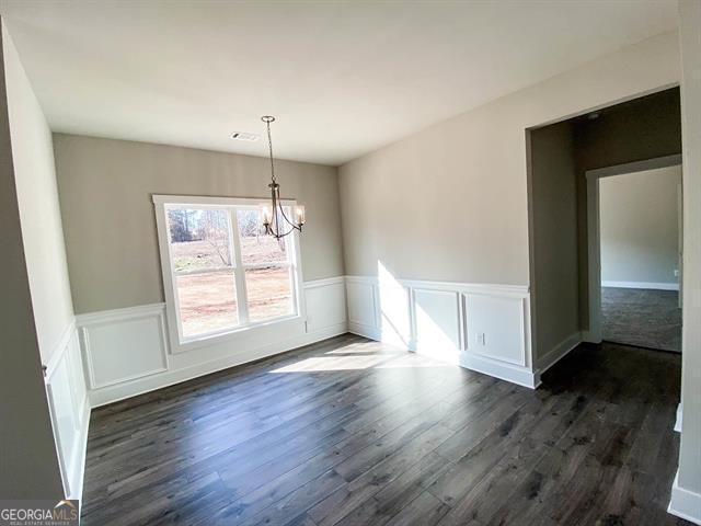 unfurnished dining area featuring a chandelier and dark hardwood / wood-style flooring