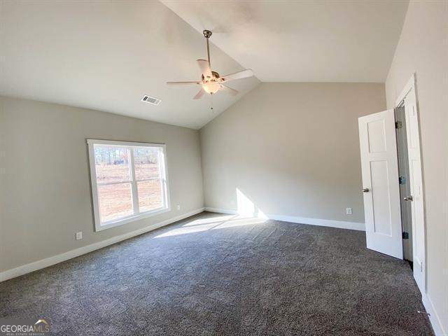 carpeted empty room with ceiling fan and vaulted ceiling