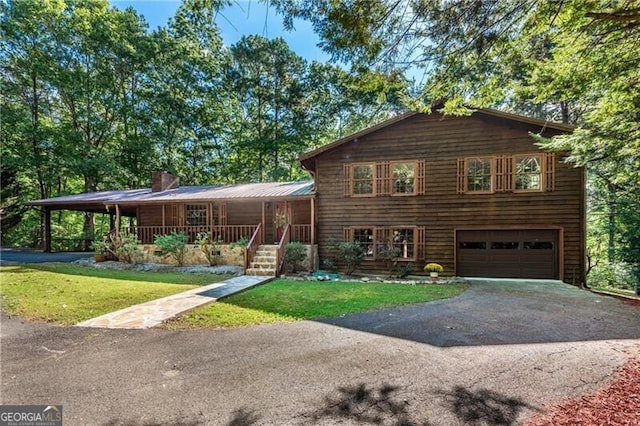 tri-level home featuring covered porch, a garage, and a front lawn