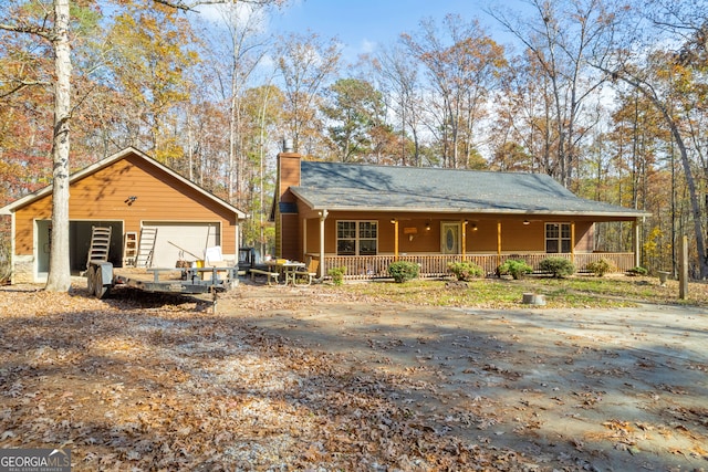 view of front of property with covered porch, a garage, and an outdoor structure