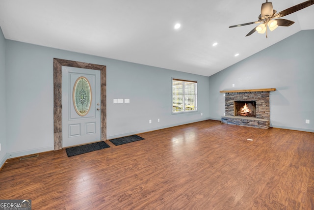 unfurnished living room featuring wood-type flooring, vaulted ceiling, ceiling fan, and a stone fireplace