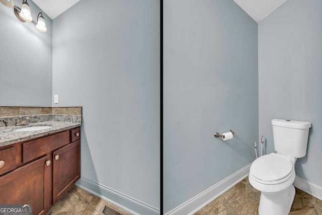 bathroom featuring a textured ceiling, vanity, and toilet