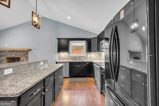 kitchen featuring stainless steel appliances, vaulted ceiling, dark wood-type flooring, sink, and pendant lighting