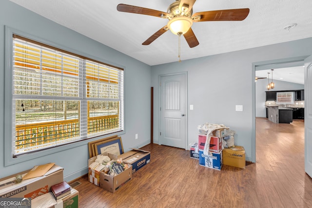 game room with hardwood / wood-style flooring, ceiling fan with notable chandelier, a textured ceiling, and vaulted ceiling