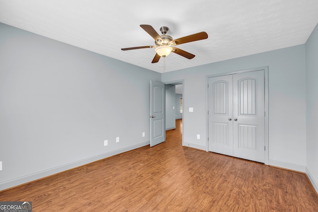 unfurnished bedroom featuring ceiling fan, a closet, and light hardwood / wood-style flooring