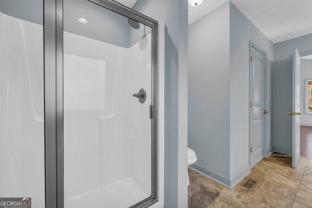 bathroom featuring a textured ceiling, toilet, and an enclosed shower