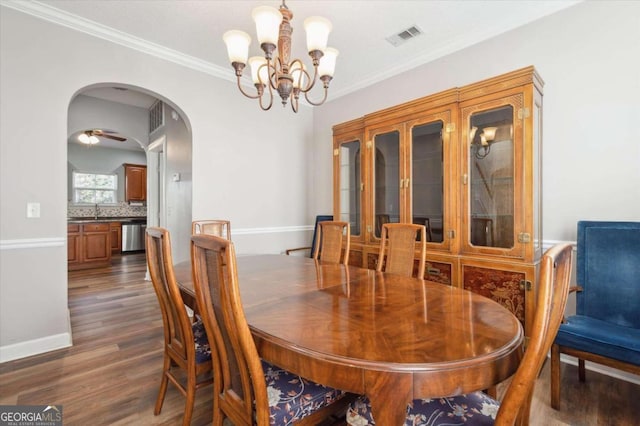 dining area featuring a notable chandelier, sink, ornamental molding, and dark wood-type flooring