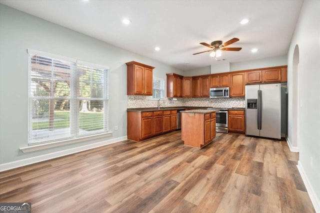 kitchen with sink, a center island, stainless steel appliances, backsplash, and hardwood / wood-style flooring