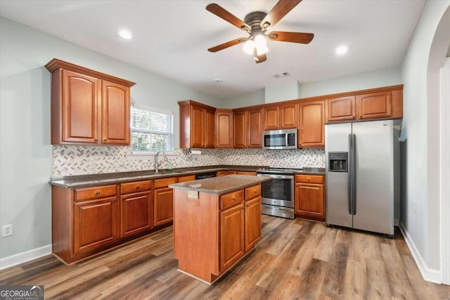 kitchen with sink, tasteful backsplash, dark hardwood / wood-style flooring, a kitchen island, and appliances with stainless steel finishes