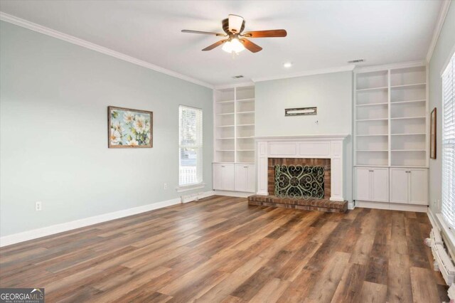 unfurnished living room with ornamental molding, built in shelves, ceiling fan, wood-type flooring, and a fireplace