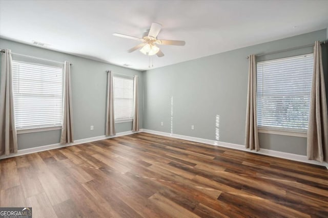 spare room featuring plenty of natural light, ceiling fan, and dark hardwood / wood-style flooring