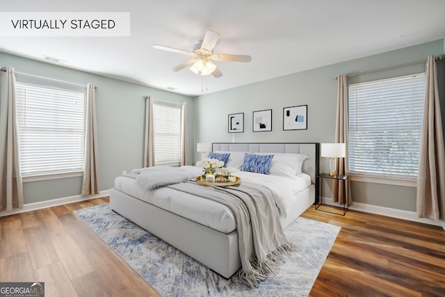 bedroom with hardwood / wood-style flooring, multiple windows, and ceiling fan