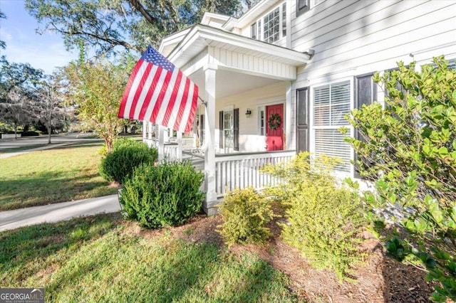 property entrance featuring covered porch and a yard