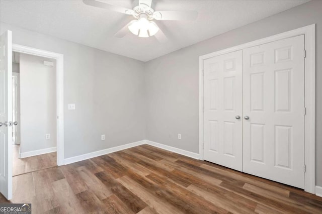 unfurnished bedroom with ceiling fan, a closet, a textured ceiling, and hardwood / wood-style flooring