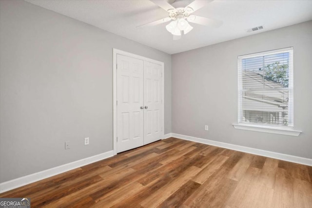 unfurnished bedroom featuring ceiling fan, a closet, and wood-type flooring