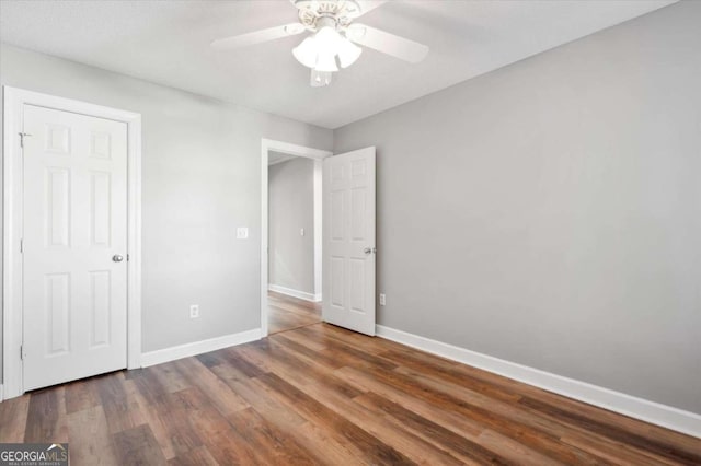 unfurnished bedroom with ceiling fan and dark wood-type flooring