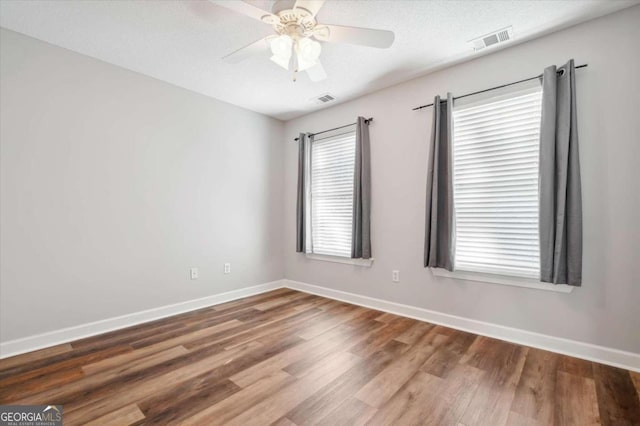 empty room with hardwood / wood-style flooring, ceiling fan, and a textured ceiling