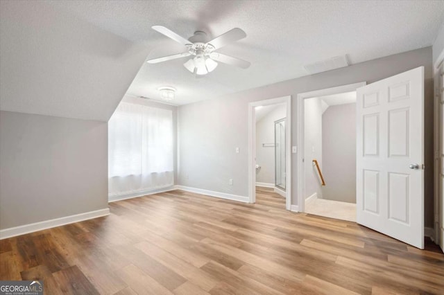 additional living space with ceiling fan, light hardwood / wood-style floors, and a textured ceiling