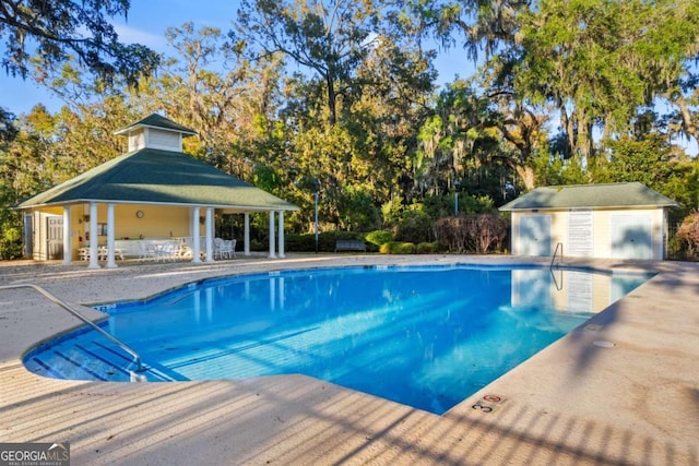 view of swimming pool featuring an outbuilding and a patio