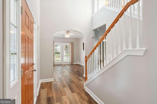 foyer featuring a towering ceiling, dark hardwood / wood-style floors, ceiling fan, and crown molding