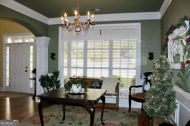 entrance foyer with an inviting chandelier, wood-type flooring, crown molding, and decorative columns