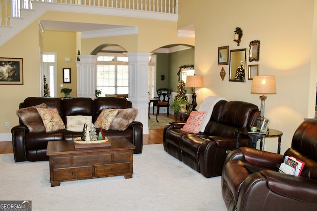 living room featuring light hardwood / wood-style floors, ornate columns, crown molding, and a high ceiling