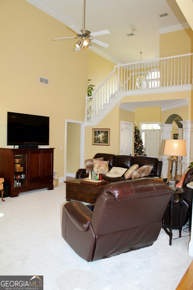 living room featuring ceiling fan, crown molding, light carpet, and a high ceiling