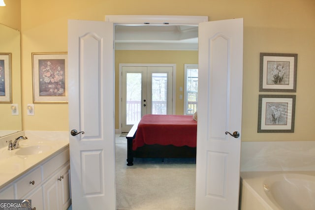 bathroom featuring vanity, a washtub, and french doors