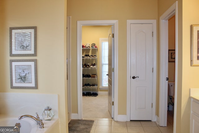 bathroom with tile patterned flooring, vanity, and a tub to relax in