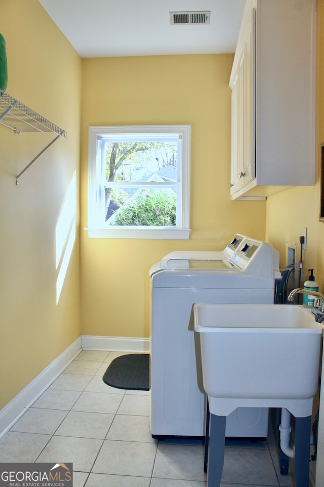 laundry room featuring cabinets, light tile patterned floors, and separate washer and dryer