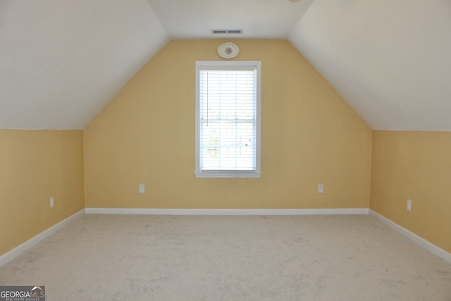 bonus room with light colored carpet and vaulted ceiling