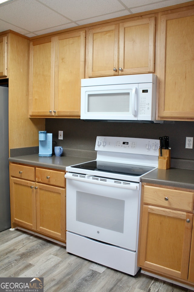 kitchen featuring white appliances, light hardwood / wood-style floors, and a paneled ceiling