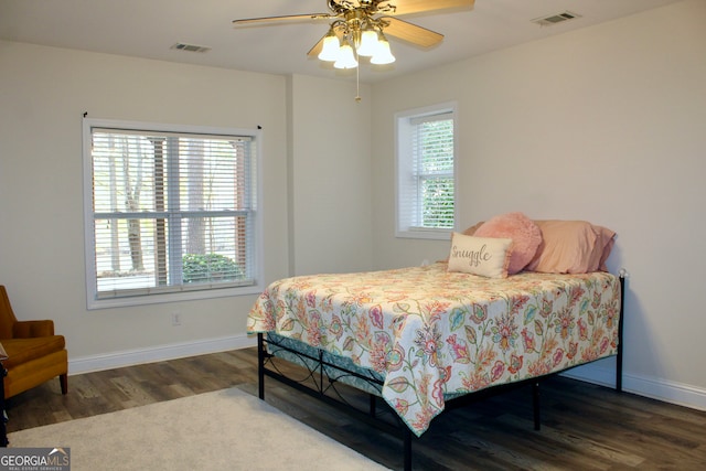 bedroom with ceiling fan, dark wood-type flooring, and multiple windows